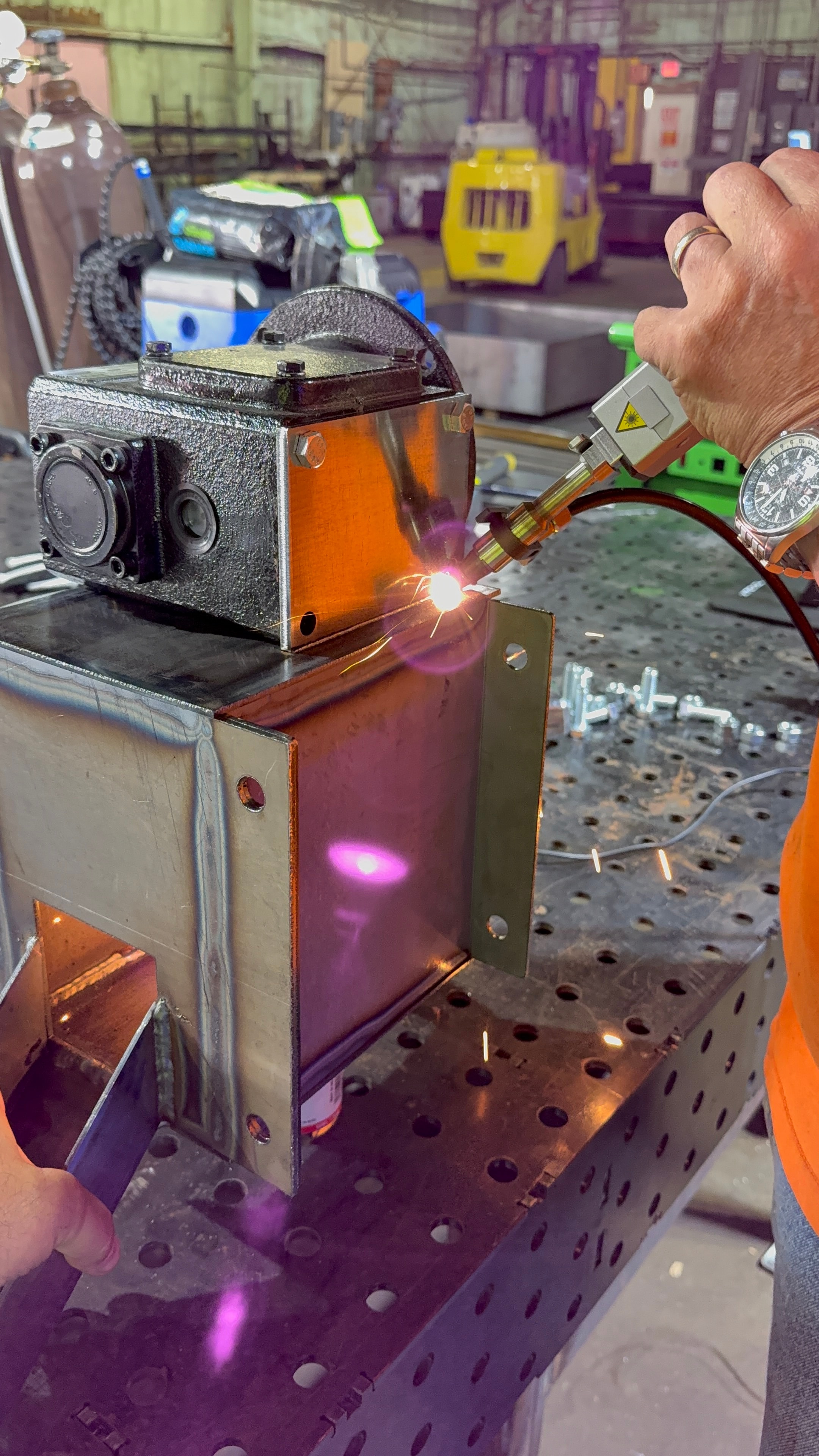 Handheld laser welder with sparks on shop floor