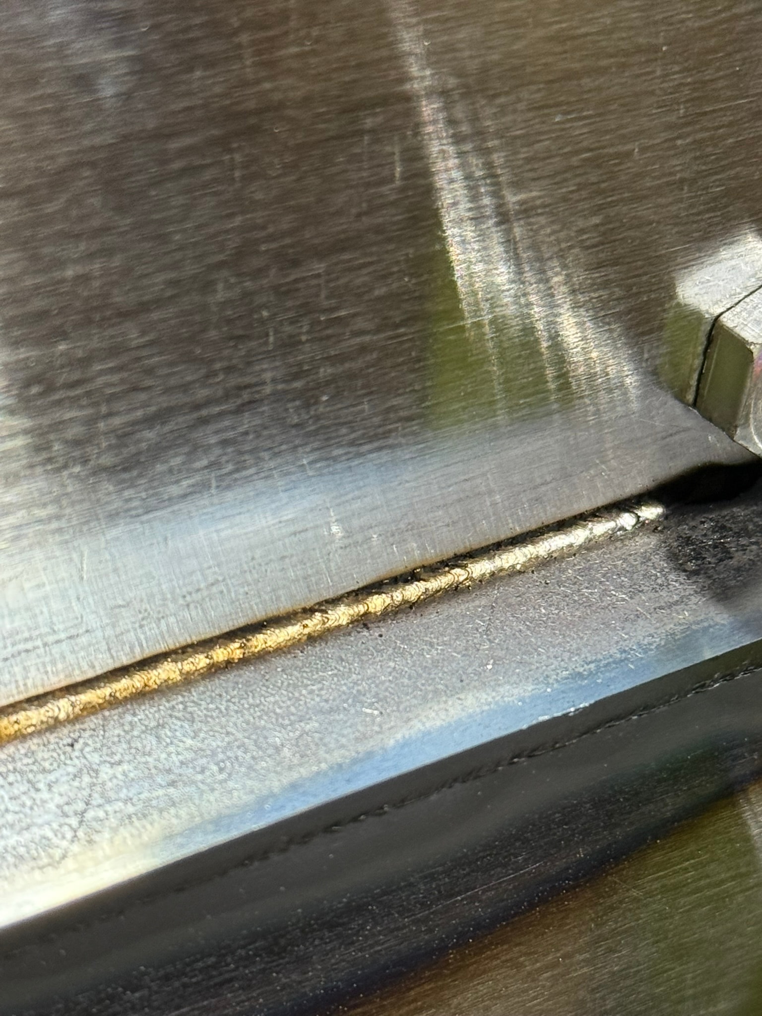 Close-up laser weld bead on steel with gold and blue heat tint