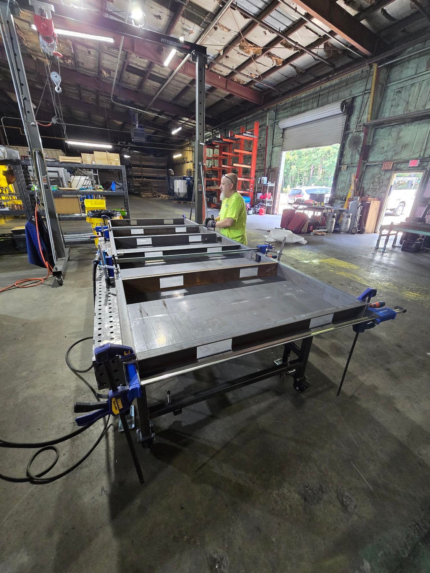 Welder assembling a large aluminum frame in the shop