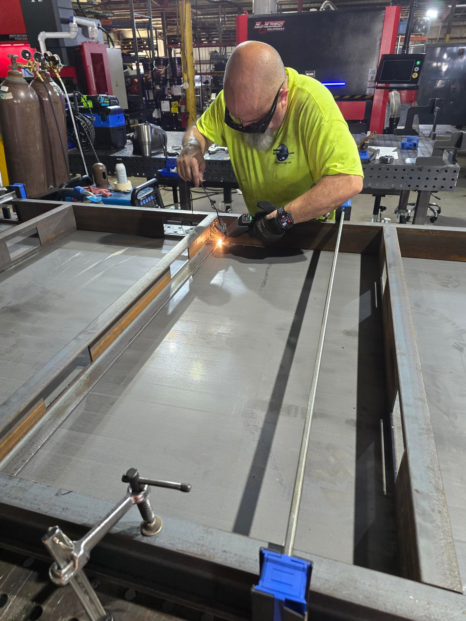 Welder striking an arc on a large steel panel in the shop